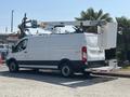 A white 2019 Ford Transit 350 with a utility bucket lift attached to the roof parked on a gravel surface