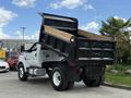 A 2017 Ford F-750 dump truck with its bed raised and wooden planks in the back showing the truck's capacity for transporting materials