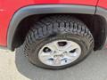 Close-up of the tire and wheel of a 2015 Jeep Grand Cherokee featuring a rugged tread pattern and a silver alloy wheel