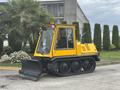 A yellow 2004 Bombardier SW48 snowcat with a front snowplow attachment and wide tracks for snow and terrain navigation