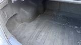 The trunk of a 2018 Hyundai Sonata with a gray carpet lining showing some scattered debris and an empty compartment