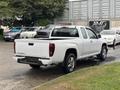 A white 2011 Chevrolet Colorado pickup truck with a short bed and chrome wheels parked on a wet surface