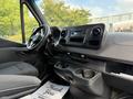 Interior view of a 2021 Mercedes-Benz Sprinter with black seats dashboard and console featuring controls and cup holders