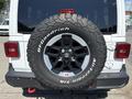 A 2021 Jeep Wrangler with a black spare tire mounted on the rear featuring a silver rim and white lettering on the tire