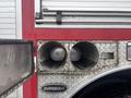 Two large round exhaust pipes with a diamond plate surface and a visible logo labeled "SUPERIOR" on the side of a red fire truck