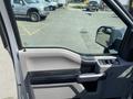 A 2015 Ford F-150 interior door panel features a black armrest and controls for windows and locks