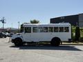 A 2013 International CE300 school bus with a white exterior parked with side view showing multiple windows and a black tire at the bottom