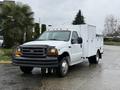 A 2000 Ford F-450 truck with a white exterior and a utility box in the back, featuring black bumpers and visible headlights