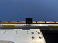 A roof-mounted light on a silver Workhorse W62 vehicle with visible screws and yellow tubing along the side