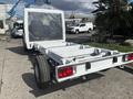 A 2023 RAM Promaster 3500 chassis cab with an open cargo area and no attached bodywork showcasing the structural frame and rear lights