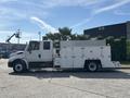 A 2006 International 4300 truck with a white utility body featuring a toolbox and equipment storage compartments