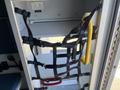 A 2013 Chevrolet Express interior with black webbing straps and a yellow handle used for securing equipment or cargo in place