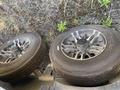 Two black wheels with silver rims from a 2021 Grand Design Recreational ST3478MBS camper are positioned on a gravel surface