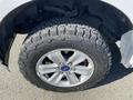 A close-up of a 2018 Ford F-150 wheel with a silver alloy rim and a rugged all-terrain tire showing detailed tread patterns