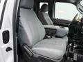 Interior of a 2015 Ford F-450 featuring gray upholstered front seats with a central armrest and control panels on the driver's side