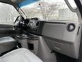 Interior view of a 2019 Ford Econoline showing the dashboard and front seats with controls and cup holders visible