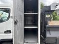 A 2015 Mitsubishi Fuso FE160 with an open storage compartment featuring two shelves inside