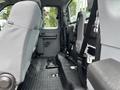Interior view of a 2013 Ford F-250 SD cab with gray fabric seats and black floor mat showing space and seatbelt attachments on the back wall