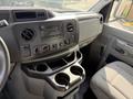 Interior dashboard of a 2019 Ford Econoline featuring a radio and climate controls with cup holders and a driver's seat in view