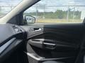 A 2015 Ford Escape with a black interior featuring a driver's side door panel and armrest with controls for windows and locks