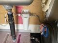 A 2008 Wells Industries Inc EW1422 water filtration system mounted on a wall with plumbing connections and a clear filter housing