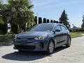 A blue 2018 Kia Rio5 parked on a driveway with a sleek design featuring a hatchback body style and modern headlights