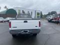A white 2005 Ford F-350 SD with a utility bed and a metal mesh tool rack positioned at the rear