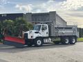 A 2013 Freightliner 114SD truck with a snow plow attached in the front and a salt spreader in the back