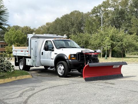 A 2007 Ford F-450 truck equipped with a red snow plow in the front and a utility bed in the back
