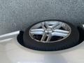 A silver 2013 Mercedes-Benz C-Class wheel with a five-spoke design and a black tire resting on its side