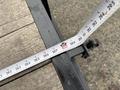 A measuring tape extends over a black metal surface showing measurements in inches and feet