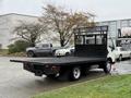 A 2015 Hino 195 flatbed truck with a black cargo bed and a metal mesh back panel parked on a street