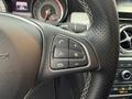 A close-up view of the steering wheel of a 2016 Mercedes-Benz GLA-250 featuring controls for audio and phone functions