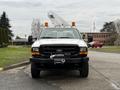 White 2001 Ford F-350 with an extended cab and a utility bucket lift attached to the top facing forward