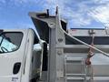 A 2013 Freightliner 114SD truck with a dump body featuring a metallic exterior and a hydraulic lifting mechanism