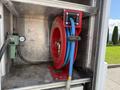 A red hose reel with blue hoses is mounted inside a metallic compartment of a vehicle