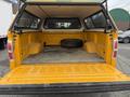 A 2014 Ford F-150 with an open bed showing a yellow interior and a spare tire placed in the center
