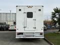 A white 2012 Ford F-550 box truck viewed from the rear with a single side door and metal steps beneath the rear bumper