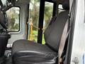 Interior view of a 2019 Chevrolet Express showing the driver's seat with a black fabric cover and a safety belt attached