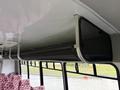 A black mesh overhead storage compartment inside a 2015 Ford Econoline bus with red patterned seats visible in the background