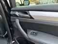 Interior door panel of a 2013 BMW X3 featuring a black leather and silver trim design with a door handle and window control button