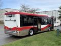 A red and silver 2016 Grande West Vicinity bus is parked with its doors open showcasing the rear and side features of the vehicle