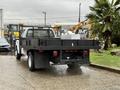 A white 2008 Ford F-350 with a black flatbed and a fenced cargo area parked on a concrete surface