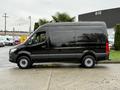 A black 2022 Mercedes-Benz Sprinter van is parked, showcasing its smooth exterior and spacious design. The vehicle has a tall profile and is equipped with standard wheels.