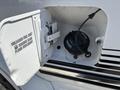 A fuel door of a 1995 Ford F-250 showing the fuel cap and warning label for unleaded fuel only