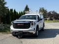 A white 2022 GMC Sierra 1500 is parked with a black grille and chrome accents featuring a large GMC logo on the front