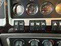 The control dashboard of a 2018 Kenworth T800 featuring various gauges and switches including start stop buttons and additional controls