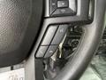 A close-up view of the steering wheel controls of a 2018 Ford F-150 featuring buttons for volume, phone, and other functions