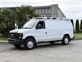 A white 2008 Ford Econoline van with a ladder rack on the roof parked on a concrete surface