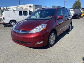 A red 2010 Toyota Sienna minivan is parked with its front slightly angled towards the viewer showcasing its sleek design and alloy wheels